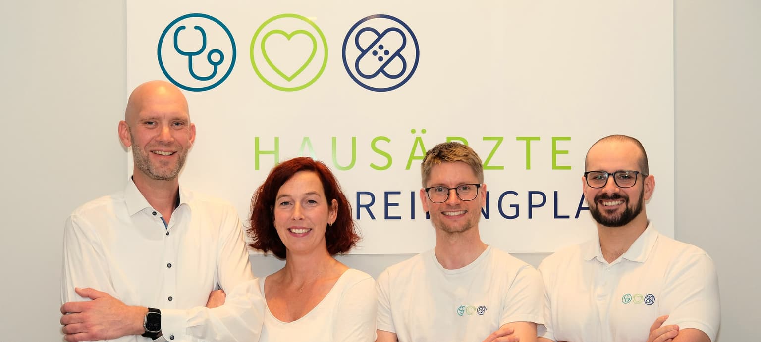 Die vier Ärzte der Hausarztpraxis am Dreiringplatz vor dem Praxisschild